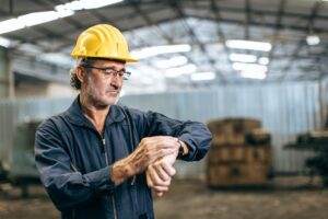 Worker checking watch to see if overtime is starting and thinking about no tax on overtime rules. 