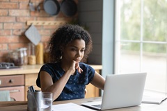 One Big Beautiful Bill Act (Trump tax plan) summary read on a laptop by a woman at a table.